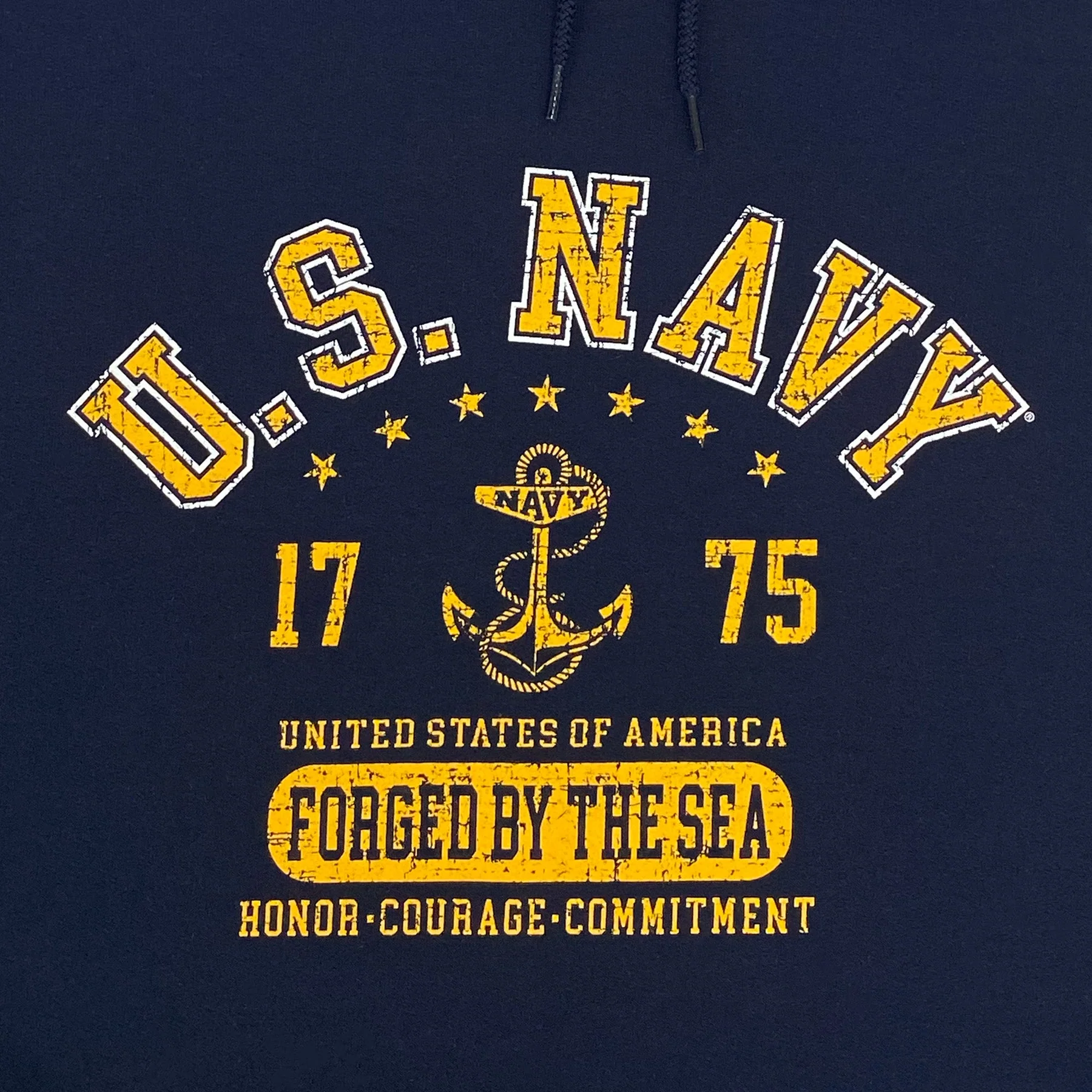Closeup of U.S. Navy "Forged By The Sea" distressed screen print graphic with anchor, stars, and "Honor, Courage, Commitment" on navy blue pullover hoodie