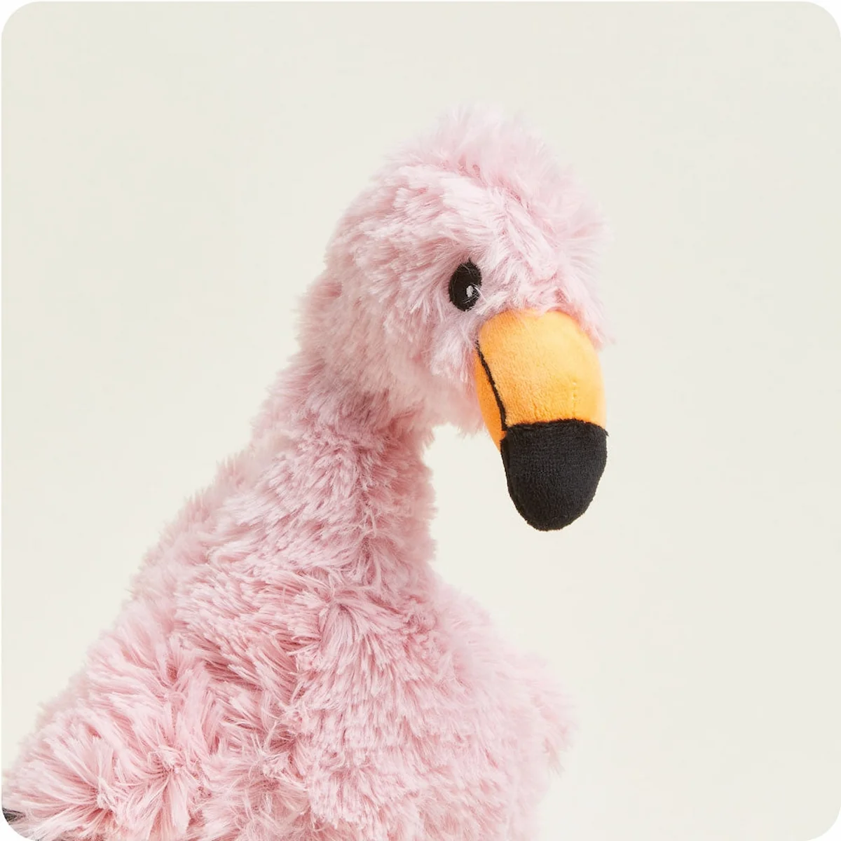 Close up of a Warmies pink flamingo plush stuffed animal from body up.